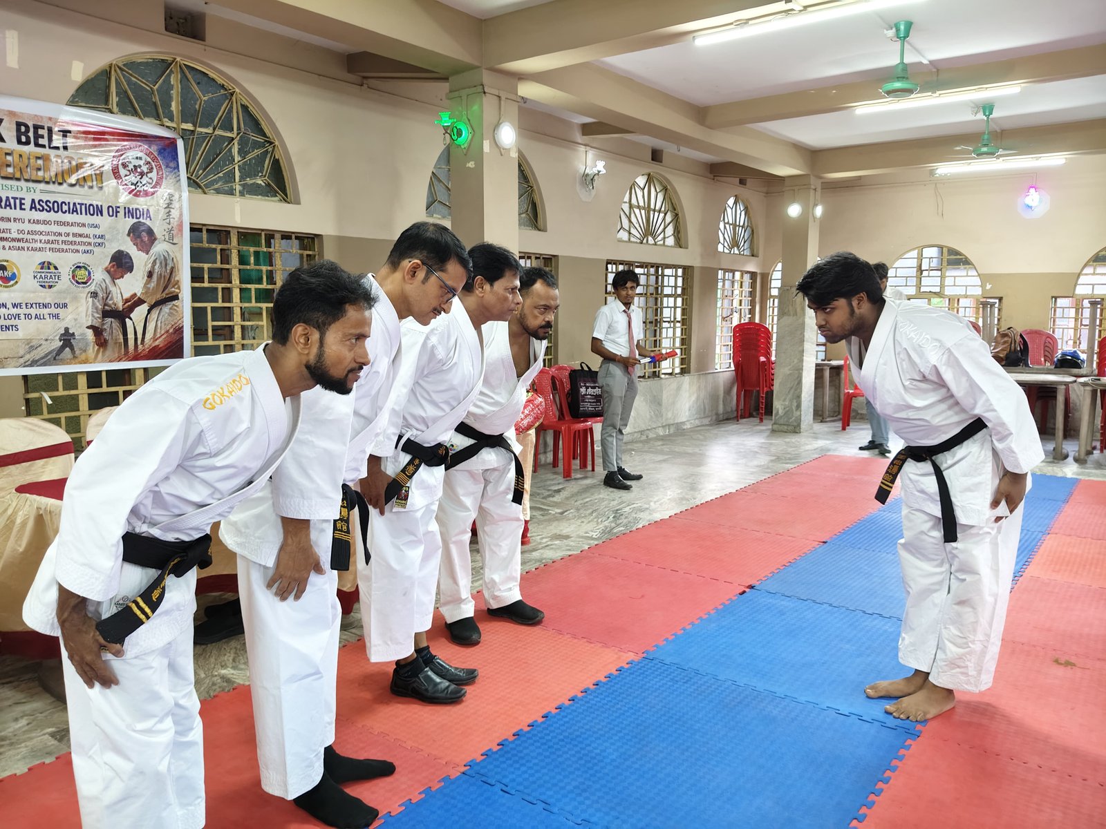 A senior instructor bowing to a black belt candidate before the award