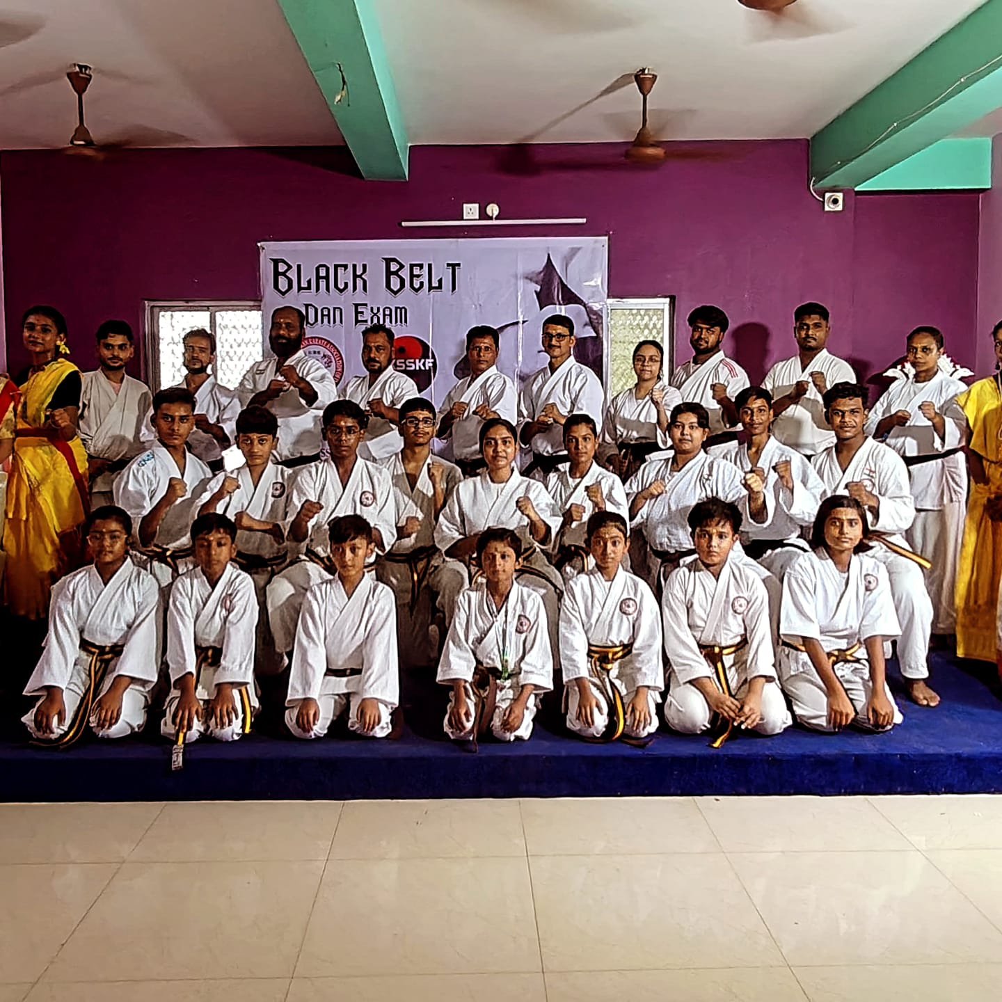 Candidates in fighting stance beneath the Black Belt Dan Exam banner