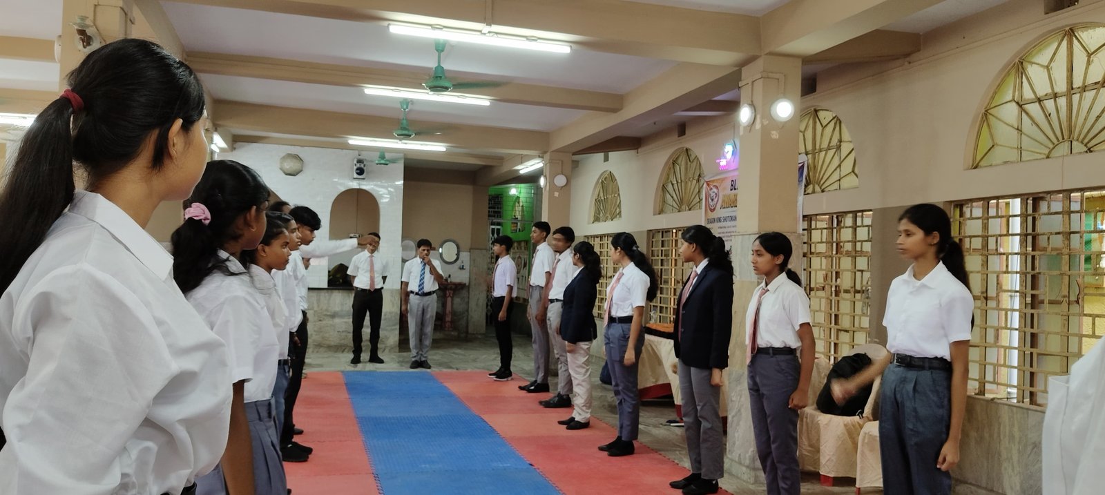 Students standing in formation, viewed from the opposite end of the hall